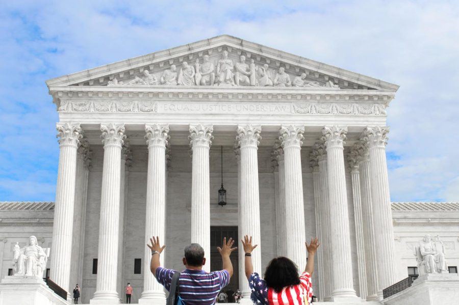 A man and wife stand before the Supreme Court, raising their hands in prayer. Over the past few weeks, hundreds of individuals have traveled to the Supreme Court to either protest the appointment of Amy Coney Barrett to the bench or demonstrate support (Photo by seniors Lexie Gagnon, Maddie Koenig, and Cole Sitilides).