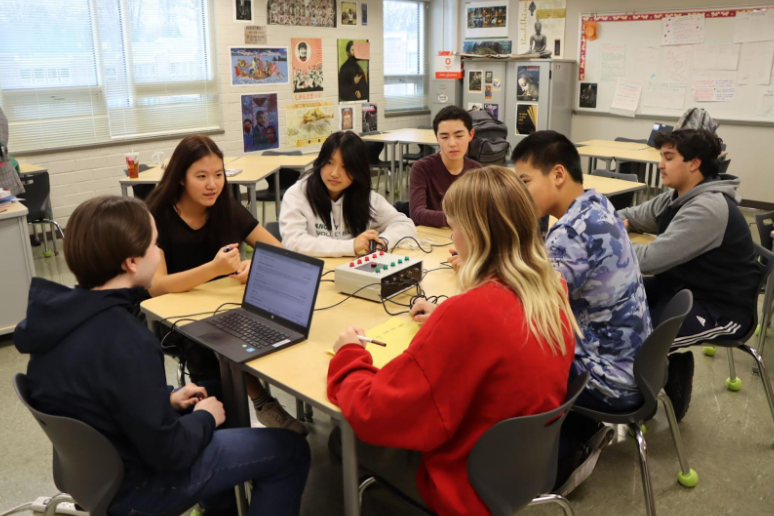 The quiz bowl team hosted an after-school practice. During practice, one person keeps track of the score, and the machine in the middle of the table indicates who has buzzed.